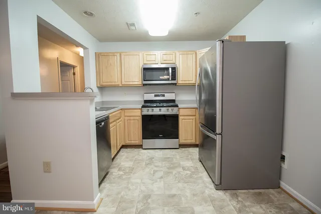 a kitchen with stainless steel appliances granite countertop a refrigerator a stove and a sink