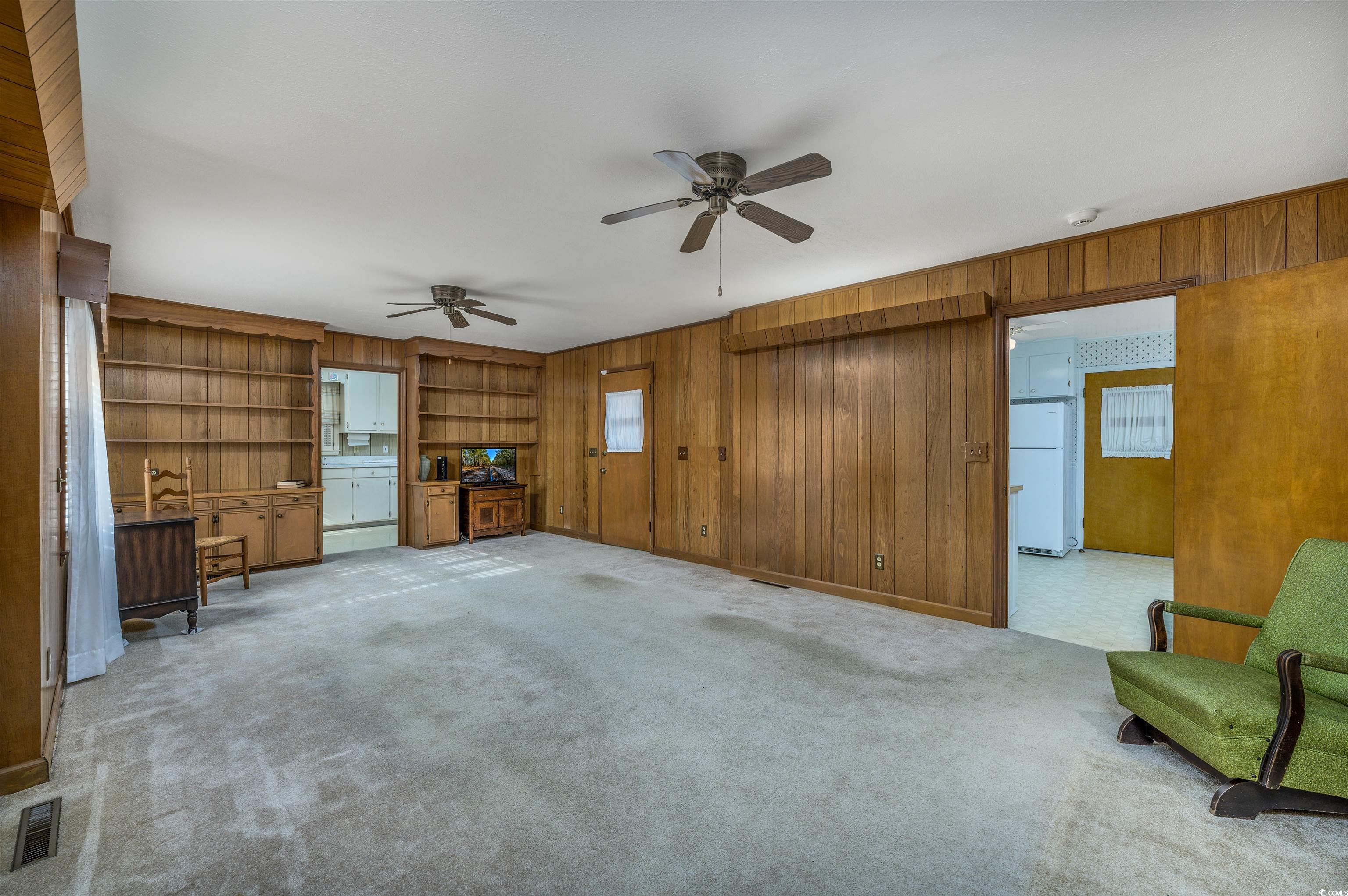 1870 Highway 348 Loris, SC 29569 - Photo 12 of 34 Unfurnished family room featuring wood walls, ceiling fan, carpet flooring, and built in shelves