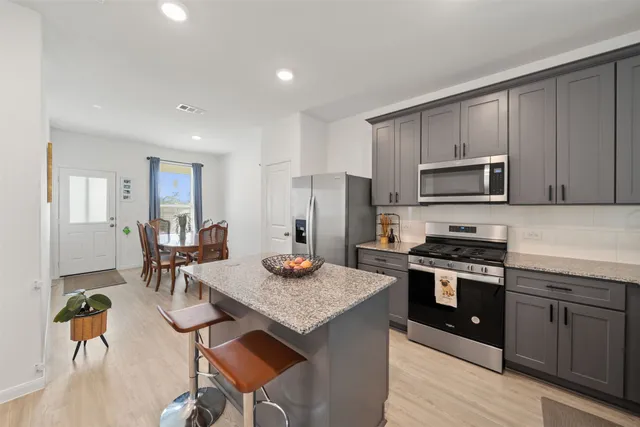 a kitchen with stainless steel appliances granite countertop a stove refrigerator and a dining table