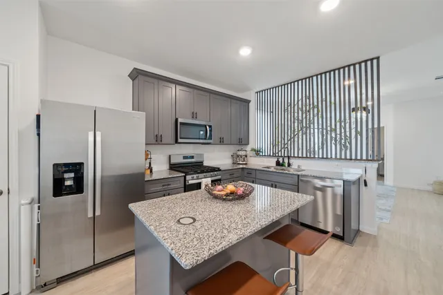 a kitchen with a refrigerator a stove a sink dishwasher and wooden cabinets with wooden floor