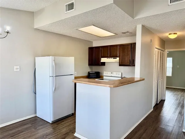 a kitchen with a refrigerator a stove top oven a sink and dishwasher with wooden floor