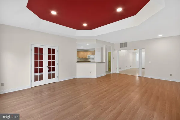 a view of an empty room with wooden floor and kitchen