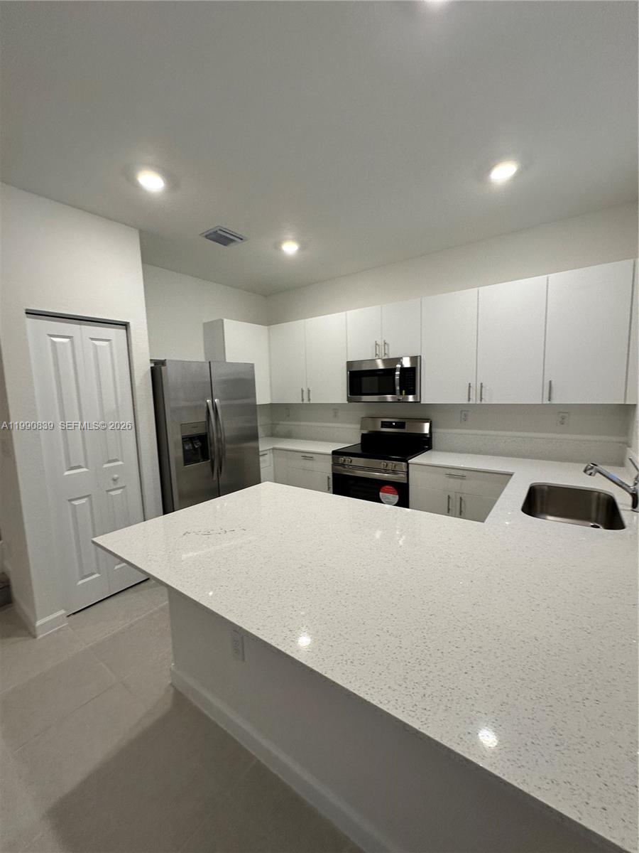 2889 Southeast 25rd, Unit 2889 Homestead, FL 33035 - Photo 4 of 23 a kitchen with refrigerator and white cabinets