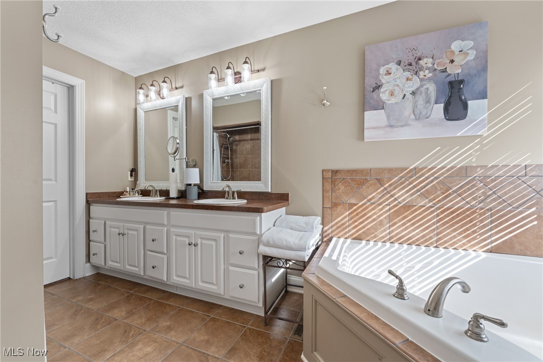 3048 Wright Road Northwest Uniontown, OH 44685 - Photo 21 of 30 Full bath with a bath, double vanity, light tile patterned floor, and walk in closet