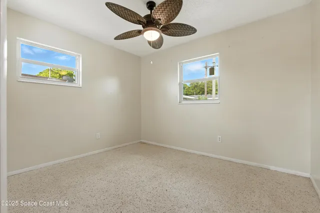 an empty room with a window and a ceiling fan