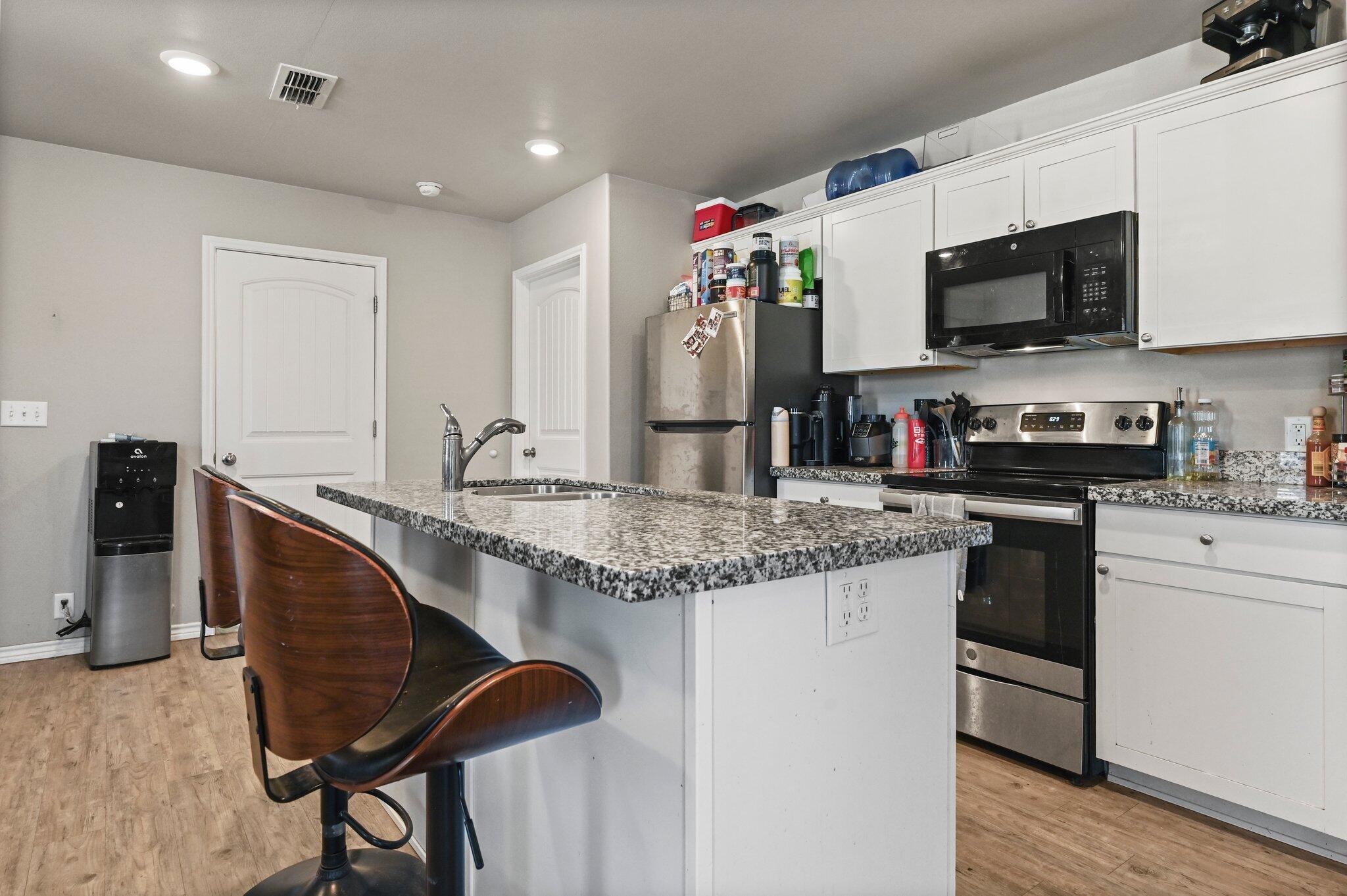 2116 24th Street, Unit 1 Lubbock, TX 79411 - Photo 4 of 13 a kitchen with granite countertop a sink stainless steel appliances and cabinets