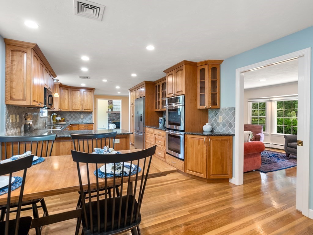 123 Victoria Road Sudbury, MA 01776 - Photo 12 of 42 a kitchen with stainless steel appliances granite countertop a stove a refrigerator a kitchen island a dining table and chairs with wooden floor