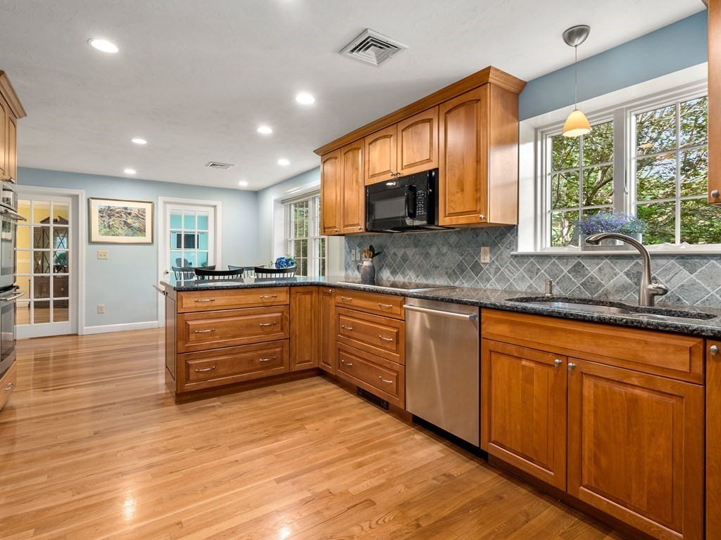 123 Victoria Road Sudbury, MA 01776 - Photo 13 of 42 a large kitchen with stainless steel appliances granite countertop a stove top oven a sink dishwasher a dining table and chairs with wooden floor