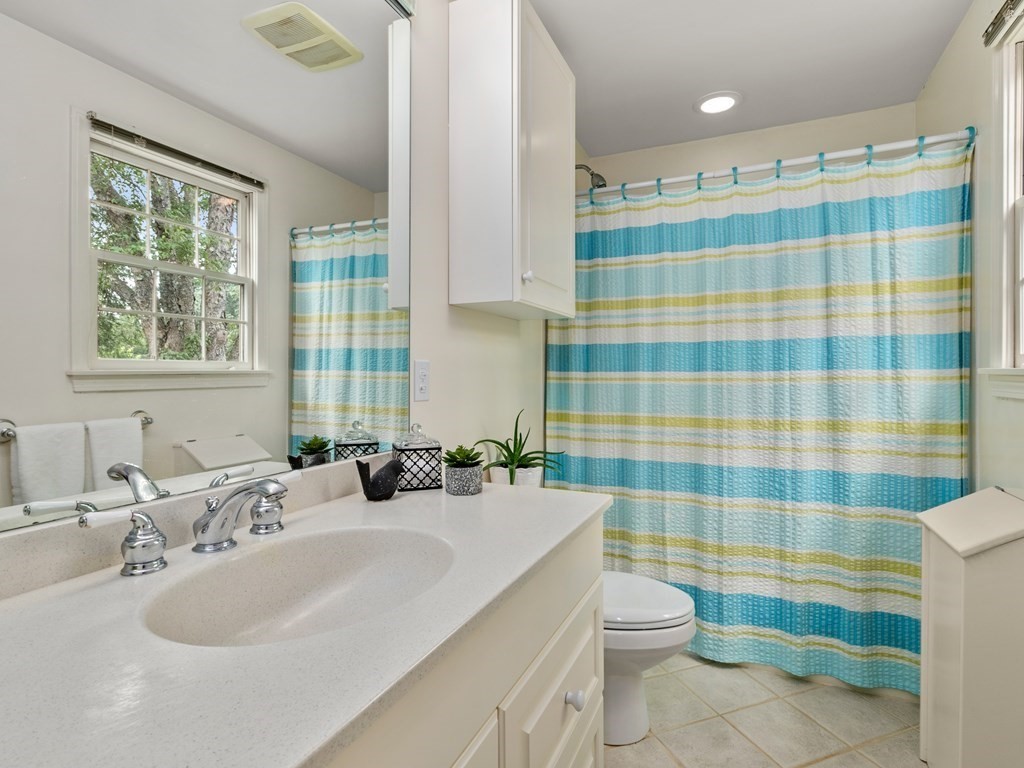 123 Victoria Road Sudbury, MA 01776 - Photo 26 of 42 a bathroom with a sink a toilet a mirror and shower curtain