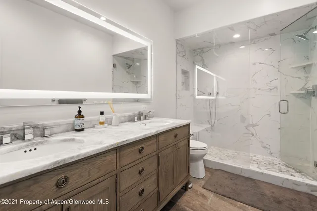 a bathroom with a double vanity sink toilet mirror and bathtub
