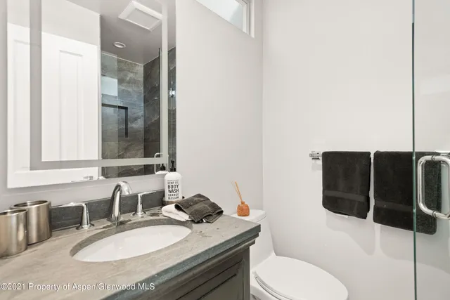 a bathroom with a granite countertop toilet sink and mirror