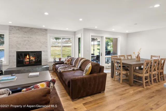 a living room with furniture a fireplace a flat screen tv and a large window