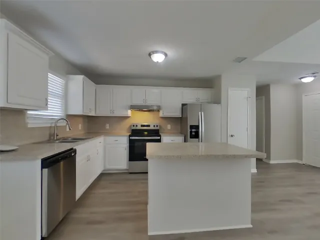 a kitchen with stainless steel appliances granite countertop a refrigerator a stove top oven a sink and dishwasher