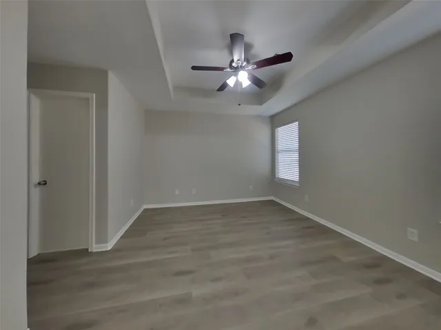 an empty room with wooden floor fan and windows