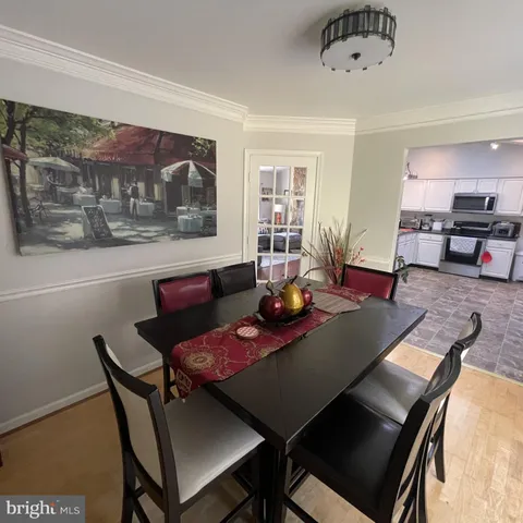 a view of a dining room and livingroom with furniture wooden floor a rug a painting and a chandelier