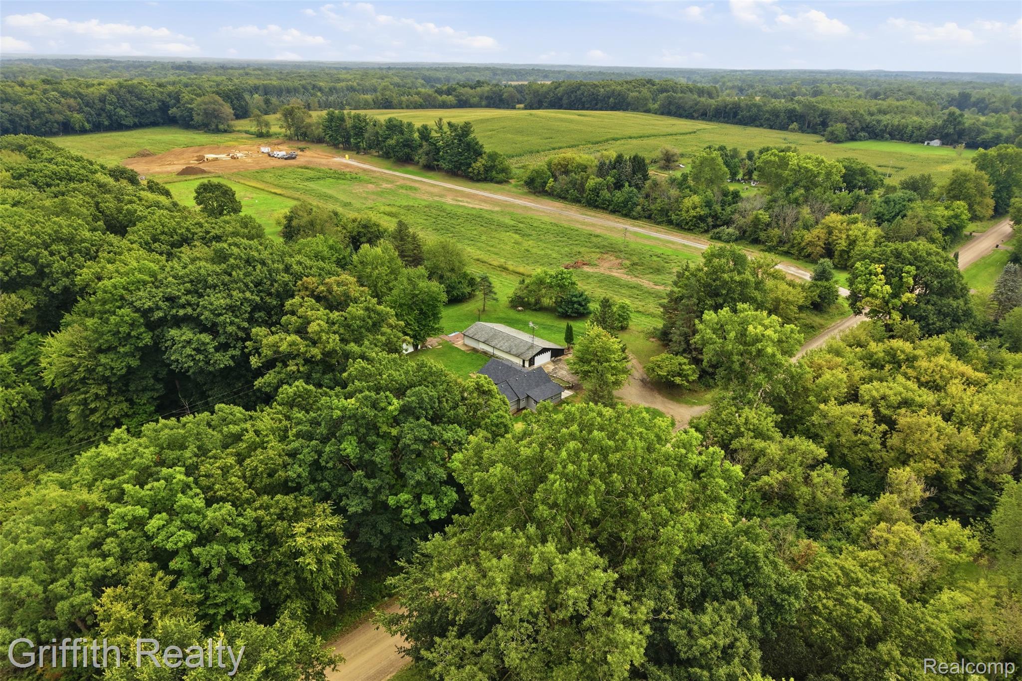 5820 Mack Road Howell, MI 48855 - Photo 51 of 60 Sprawling rural property featuring a modern agricultural structure nestled within mature hardwood forest, expansive cleared pastureland, and a natural water feature traversing the grounds