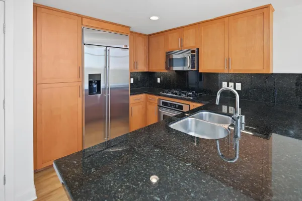 a kitchen with stainless steel appliances granite countertop a sink and a refrigerator