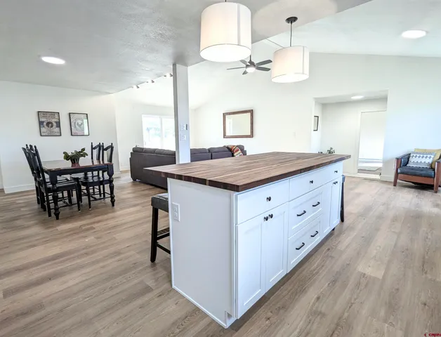 a dining hall with stainless steel appliances granite countertop a stove oven a dining table and chairs with wooden floor