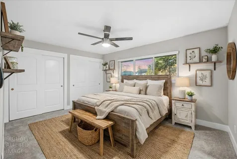 a spacious bedroom with a bed a rug and wooden floor