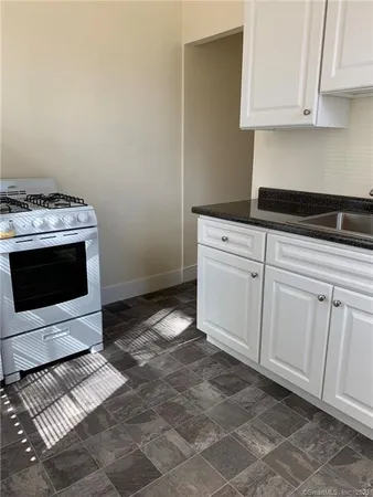 a kitchen with granite countertop white cabinets and white appliances