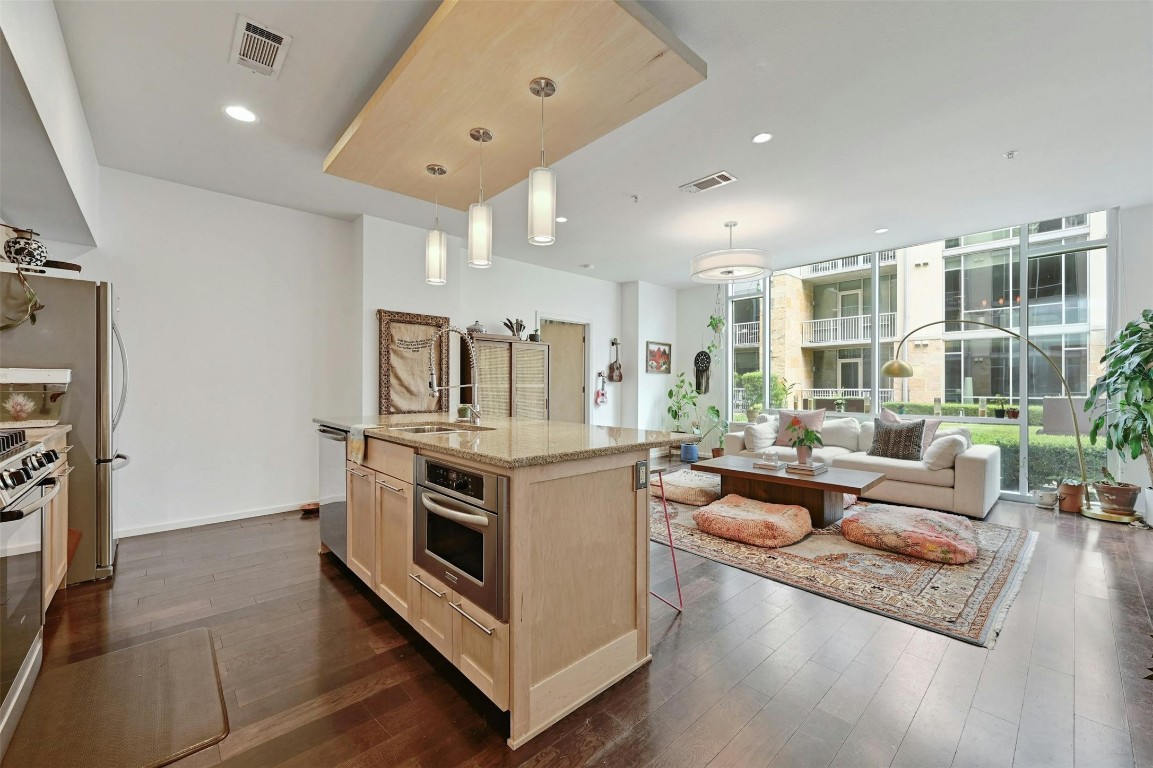 a large living room with stainless steel appliances granite countertop a couch and a large window