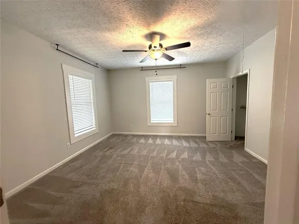 an empty room with windows and ceiling fan