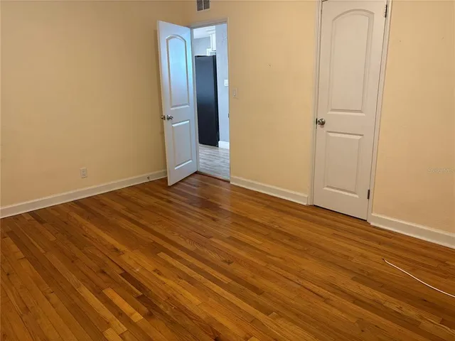 an empty room with wooden floor and closet