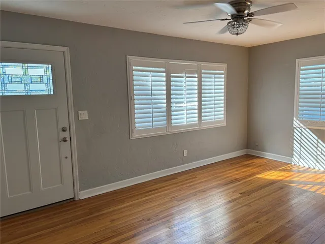 a view of an empty room with a window and wooden floor