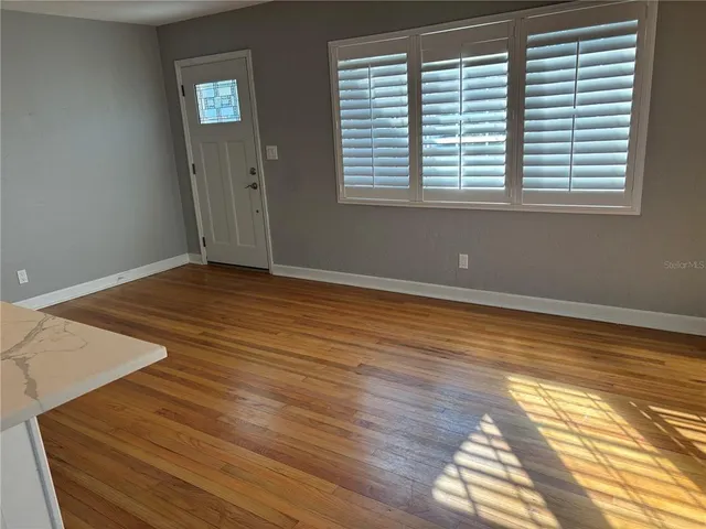 a view of an empty room with wooden floor and a window