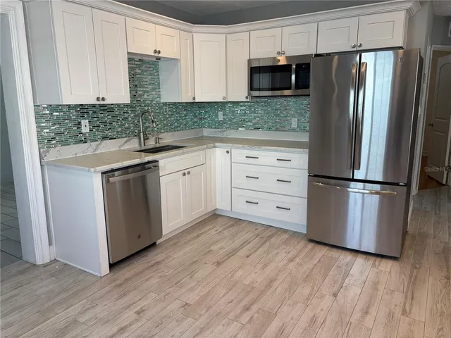 a kitchen with stainless steel appliances granite countertop a refrigerator and a sink
