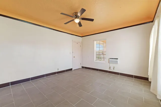 an empty room with windows and fan