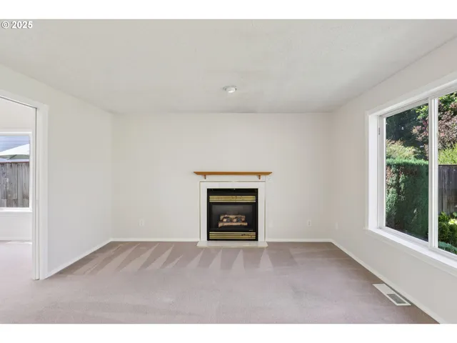 a view of an empty room with a window and fire place