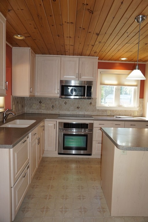 573 Reservoir Road Lunenburg, MA 01462 - Photo 7 of 26 a kitchen with stainless steel appliances granite countertop a sink a stove a microwave and wooden cabinets