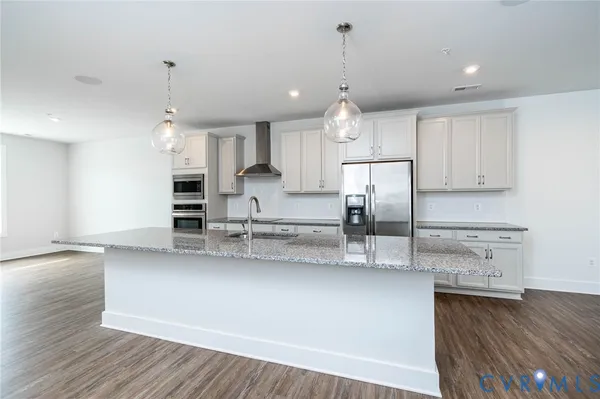 a kitchen with kitchen island a counter top space a sink stainless steel appliances and cabinets