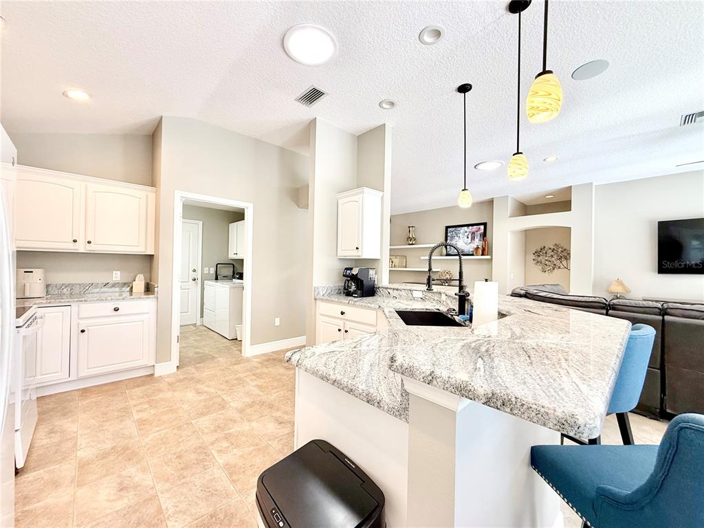 3088 Berwyn Way The Villages, FL 32162 - Photo 16 of 60 a large kitchen with kitchen island granite countertop a sink and white cabinets