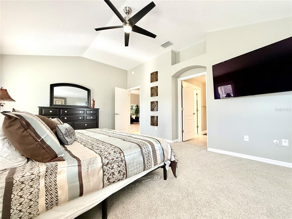 3088 Berwyn Way The Villages, FL 32162 - Photo 26 of 60 a bedroom with a large bed and a chandelier