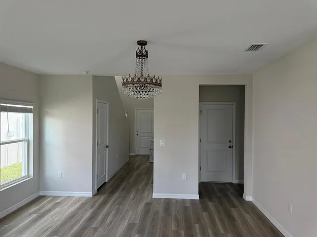 a view of an empty room with wooden floor and window