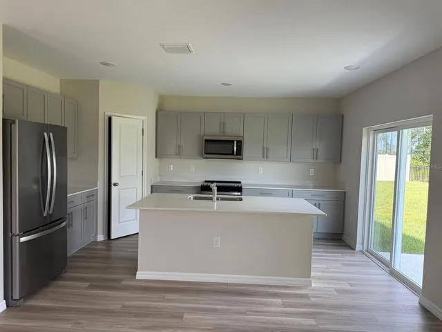 a view of a kitchen with stainless steel appliances wooden floor and large window