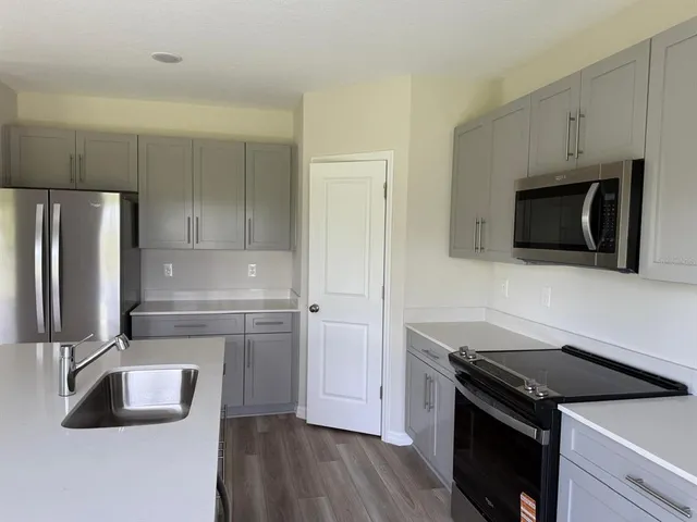 a kitchen with granite countertop a refrigerator stove and sink