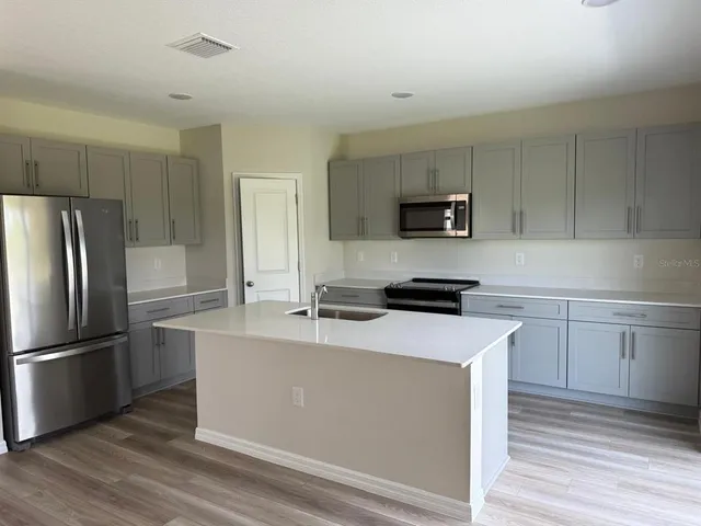 a kitchen with kitchen island a counter top space stainless steel appliances and cabinets