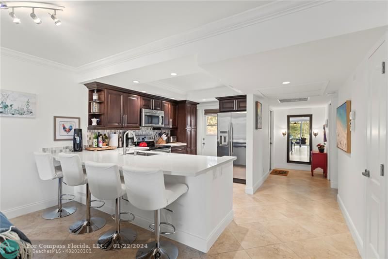a living room with stainless steel appliances furniture a dining table and kitchen view