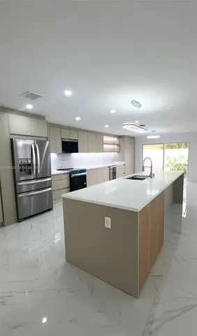 a living room with stainless steel appliances kitchen island granite countertop a sink and cabinets
