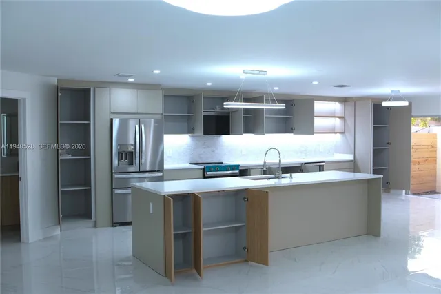 a kitchen with stainless steel appliances kitchen island a refrigerator sink and cabinets