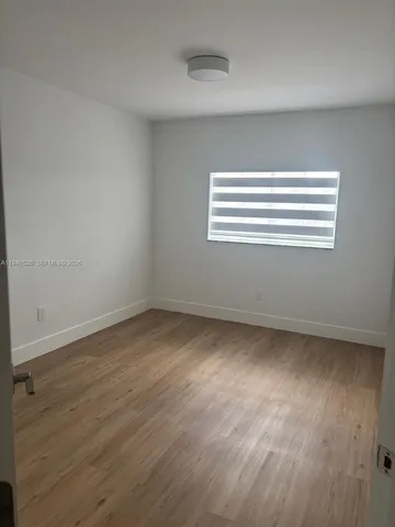 a view of empty room with window and wooden floor