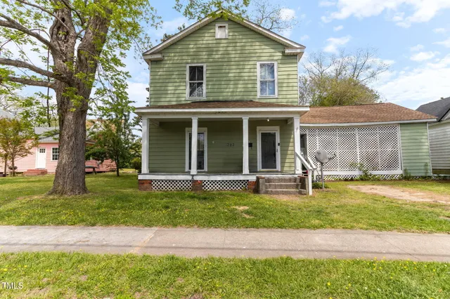 a view of a house with a yard and large tree