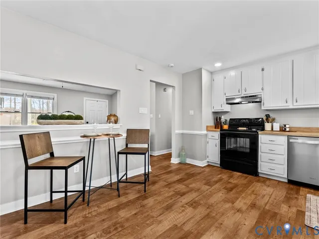 a kitchen with a refrigerator a stove top oven and white cabinets