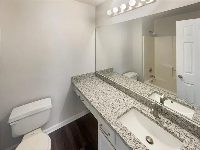 a bathroom with a granite countertop sink and a toilet