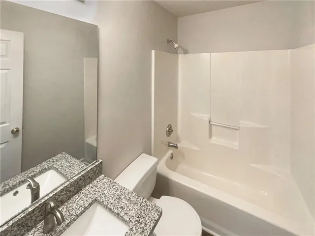 a bathroom with a granite countertop sink a toilet and bathtub