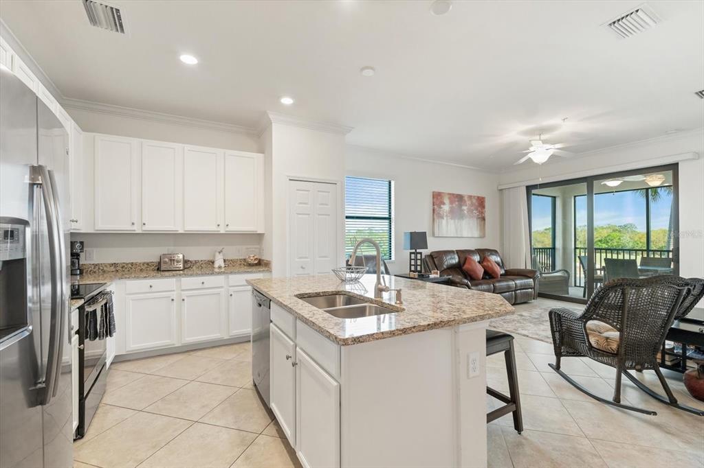 16904 Vardon Terrace, Unit 301 Lakewood Ranch, FL 34211 - Photo 7 of 53 a kitchen with a stove a sink dishwasher a refrigerator and white cabinets with wooden floor