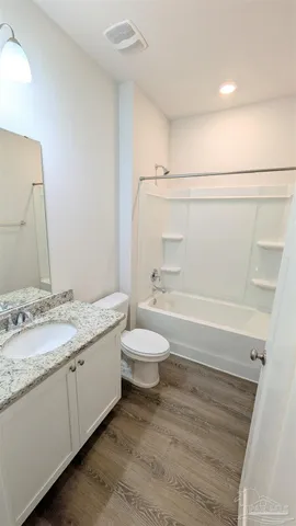 a bathroom with a granite countertop sink toilet a large mirror a bathtub and shower